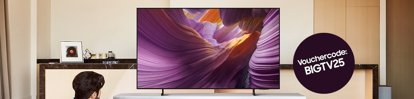 Dans un salon, on voit d'en haut une très grande télévision accrochée au mur. 