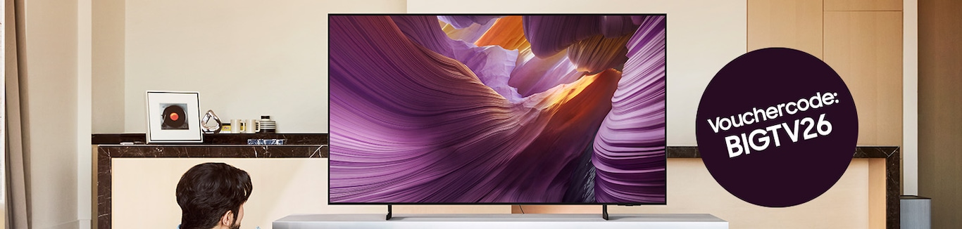 Man sieht einen OLED TV auf einem Sideboard in einem Wohnzimmer stehen. Rechts davon ist ein schwarzer Kreis mit der Inschrift Vouchercode: BIGTV26 abgebildet.
