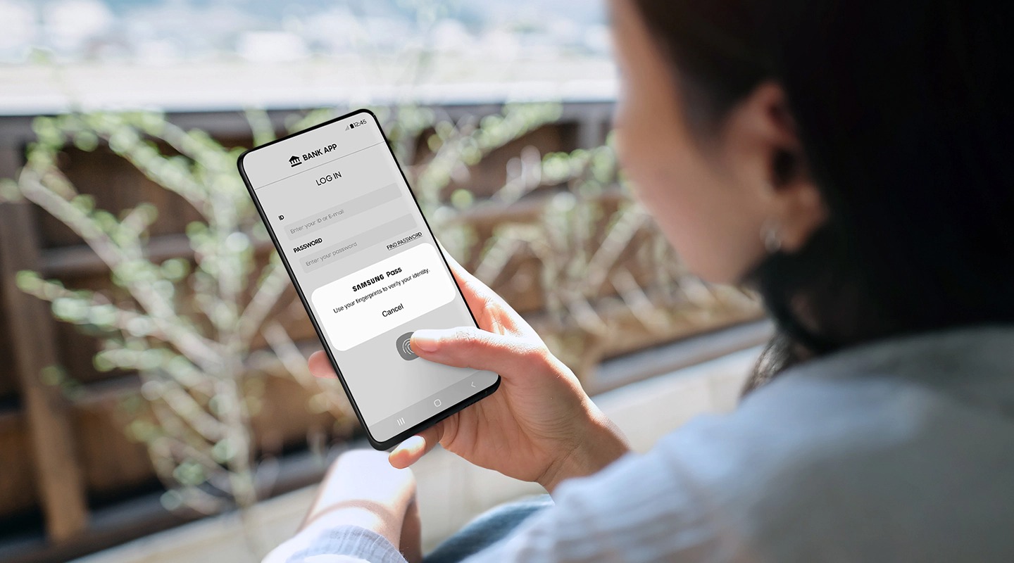 Una usuaria de un teléfono inteligente Galaxy usa su huella dactilar para autenticar un mensaje emergente de Samsung Pass a fin de iniciar sesión en su aplicación bancaria.