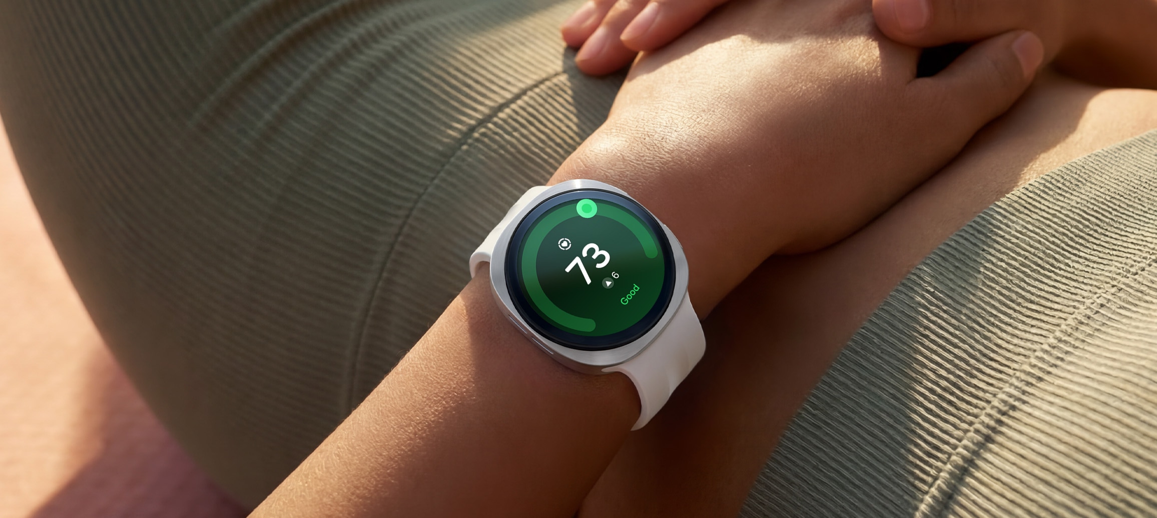 Una persona recostada boca arriba luce un Galaxy Watch9 en Silver con una correa deportiva en Cream en la muñeca, y en la pantalla del reloj se muestra una Puntuación de salud cardíaca de 73, lo que demuestra las capacidades de seguimiento de la salud cardíaca de Galaxy Watch9.