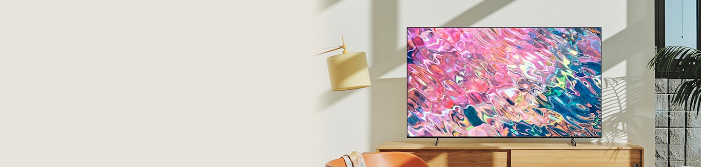 Samsung 2022 QLED, Q60B, en la esquina de una sala de estar y muestra un patrón fluido de color rosa neón en la pantalla.