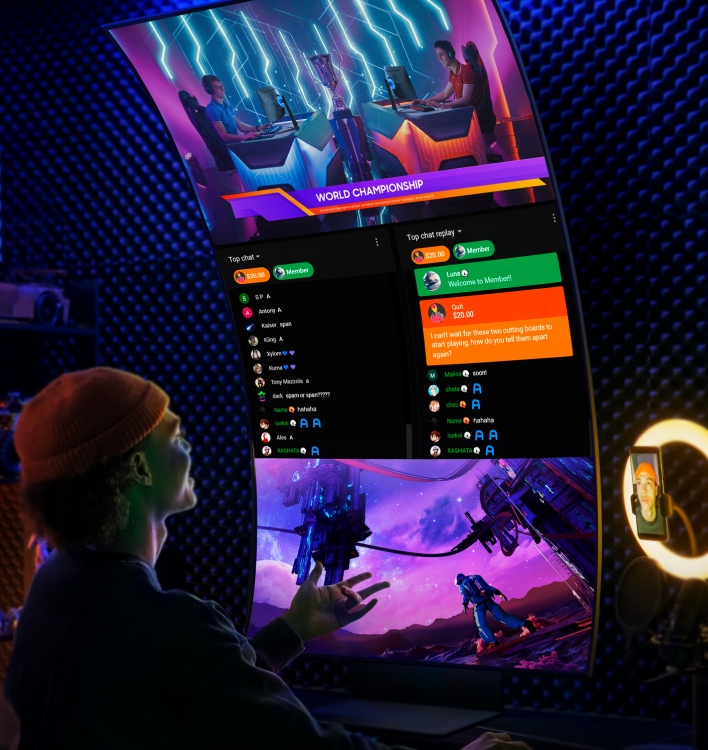 The Odyssey Ark is in vertical Cockpit Mode. A viewer watching 3 screens at once on the Ark. At the top of the screen are two competitive gamers competing in the world championship, in the middle of the screen is a chat application, and on the bottom of the screen is a game with an astronaut looking up at 2 space stations on an alien planet.