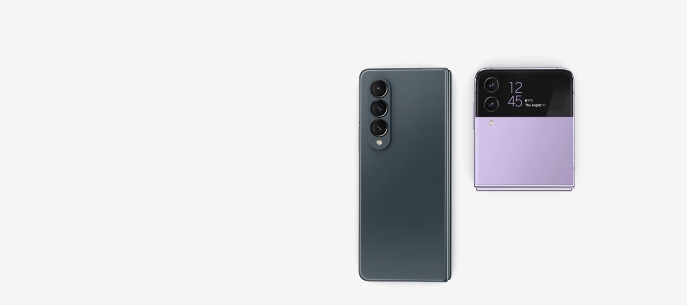 Galaxy Z Flip4 v barvě Bora Purple a Galaxy Z Fold4 v barvě Graygreen. Oba telefony jsou složené a zavřené. Zadní strana Galaxy Z Fold4 směřuje dopředu. Vnější displej a přední panel Galaxy Z Flip4 směřují dopředu. Oba telefony se zároveň otevírají. Galaxy Z Fold4 se otevře do tupého úhlu a zobrazí hlavní obrazovku s barevnou tapetou připomínající stuhu. Před ním se objeví S Pen Fold Edition. Galaxy Z Flip4 se otevře do ostrého úhlu, poté se otočí, aby se postavil jako stan, přičemž na jeho vnější obrazovce jsou zobrazeny hodiny s časem, informacemi o baterii a datem.