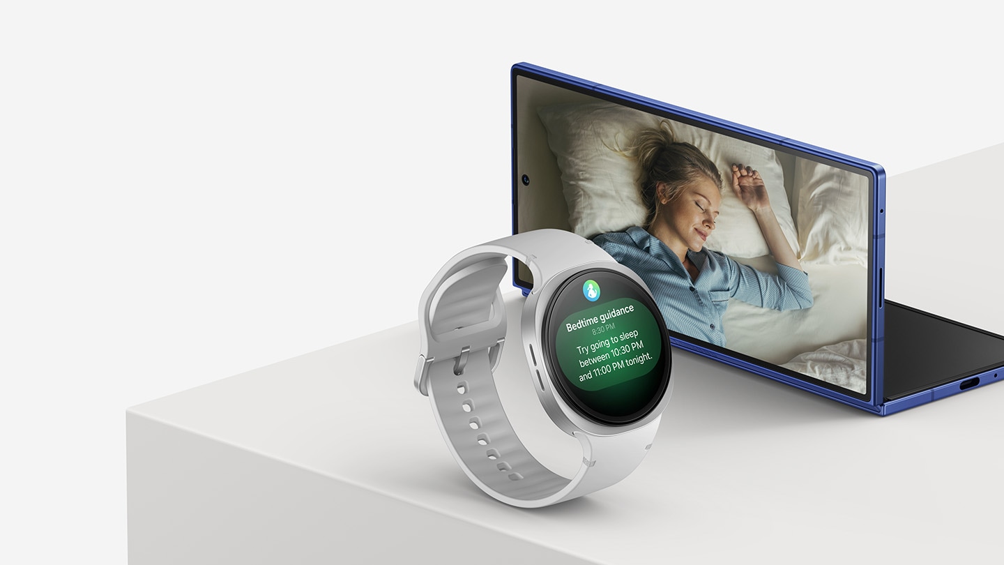 Eine Galaxy Watch8 in der Farbe Silver und ein halb aufgefaltetes Galaxy Z Fold7 in der Farbe Blue Shadow sind nebeneinander auf einer Bühne zu sehen. Das Display der Galaxy Watch8 zeigt das GUI der Schlaf-Funktion. Auf dem Frontdisplay des Galaxy Z Fold7 ist eine schlafende Frau zu sehen.