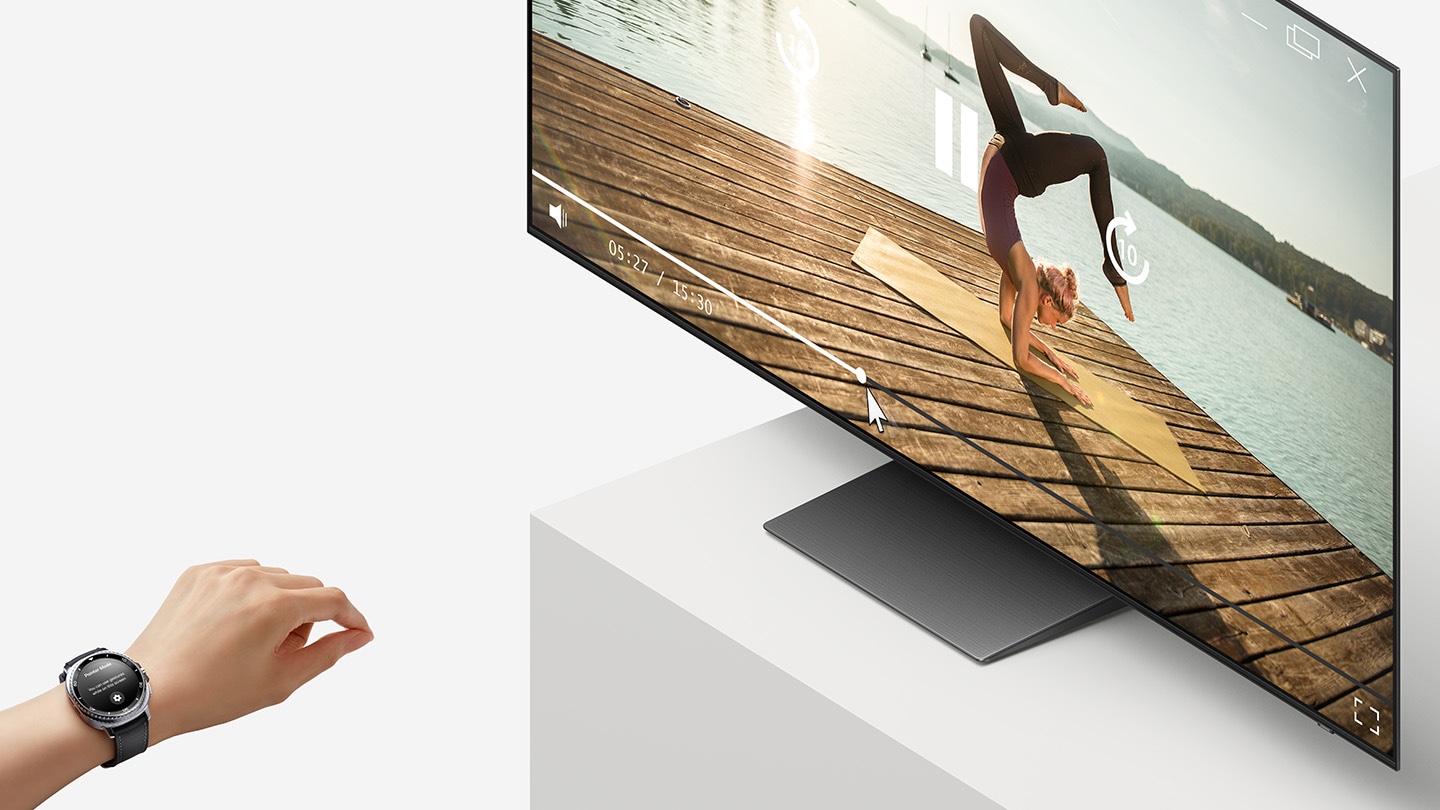 Ein OLED TV auf einer Bühne zeigt auf dem Bildschirm eine Frau, die Yoga-Übungen macht. Vor dem befindet sich eine Hand. Die Galaxy Watch8 Classic in der Farbe Black am Handgelenk zeigt die Universal Gesture GUI auf dem Display.