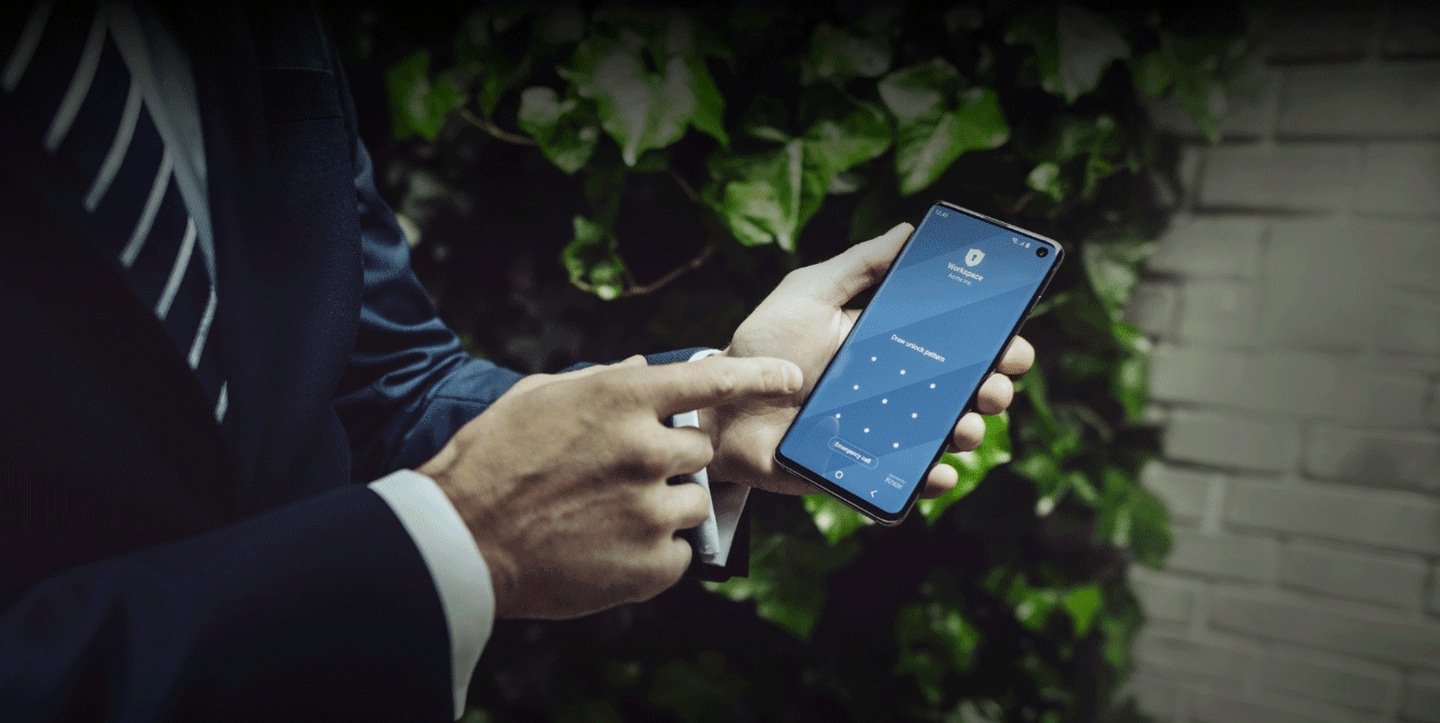 Mitarbeitender in Anzug deutet auf Samsung Device in seiner Hand, Knox-Sicherheitsscreen auf dem Device, BSI IT Sicherheit.