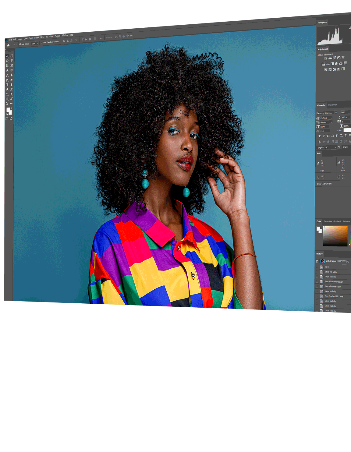 There is a photo of a model posing in front of a solid background on the monitor screen. The image is inside of a photo editing app with various editing tool options to the left and right of the photo.