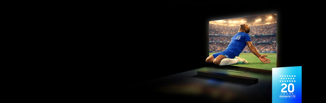 Auf einem Samsung TV mit einer Soundbar darunter ist ein Fußballspieler in einem blauen Trikot zu sehen, der in einem vollbesetzten Stadion ein Tor feiert. Auf einem Abzeichen in der Ecke steht der Text: „20 Jahre Globale Nr. 1 TV“.
