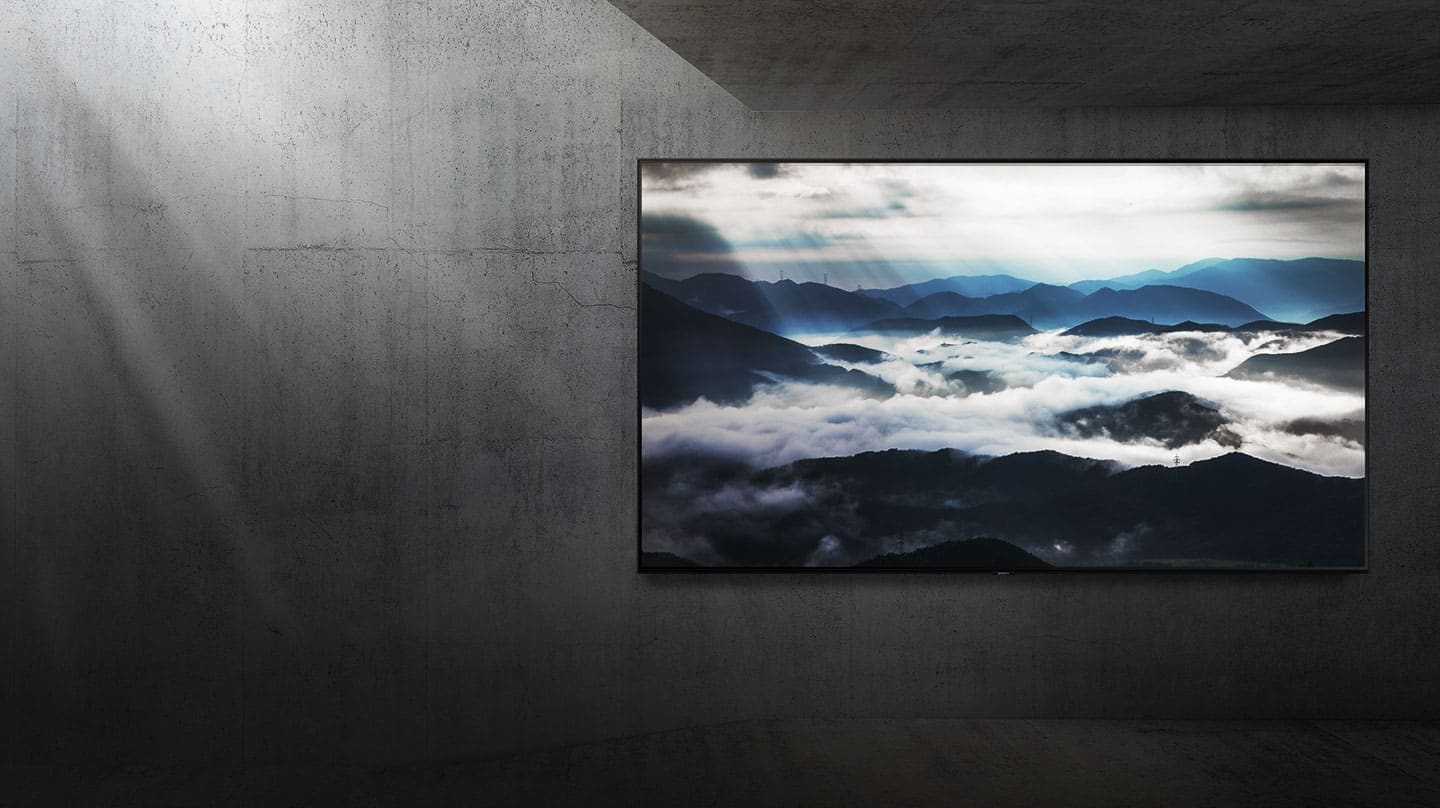 Ein großes TV-Gerät, das an einer Beton-Wand angebracht ist, zeigt eine Landschaftsszene in 4K-Auflösung, während von links Sonnenlicht ins Bild fällt. 