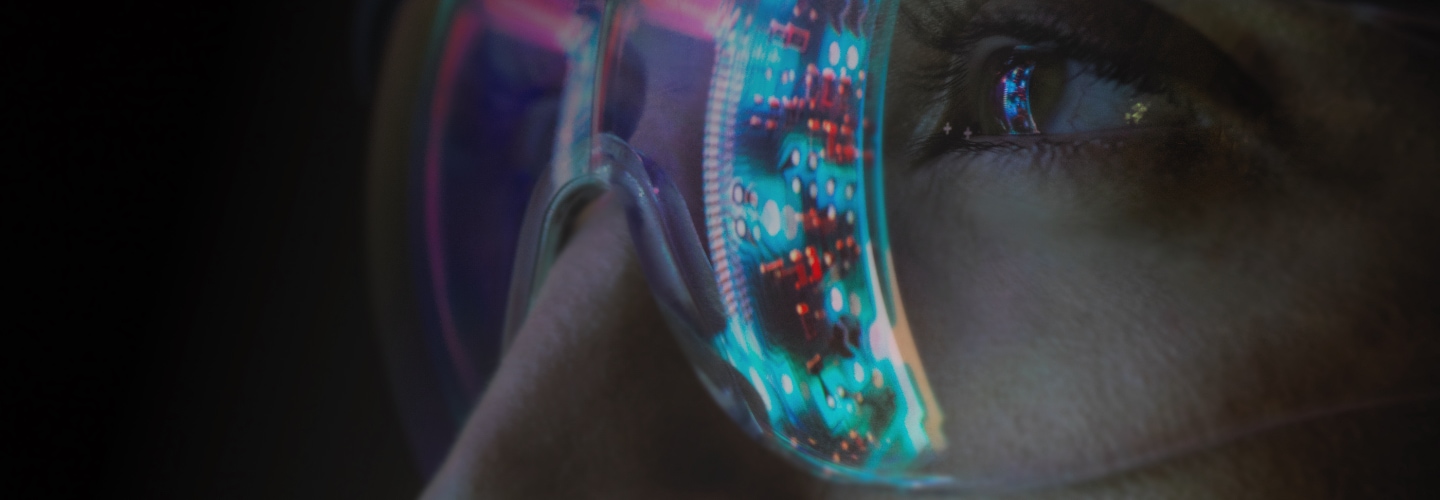 Close-up view of a woman's eyes wearing goggles with a reflected image of a circuit board visible on the lens.