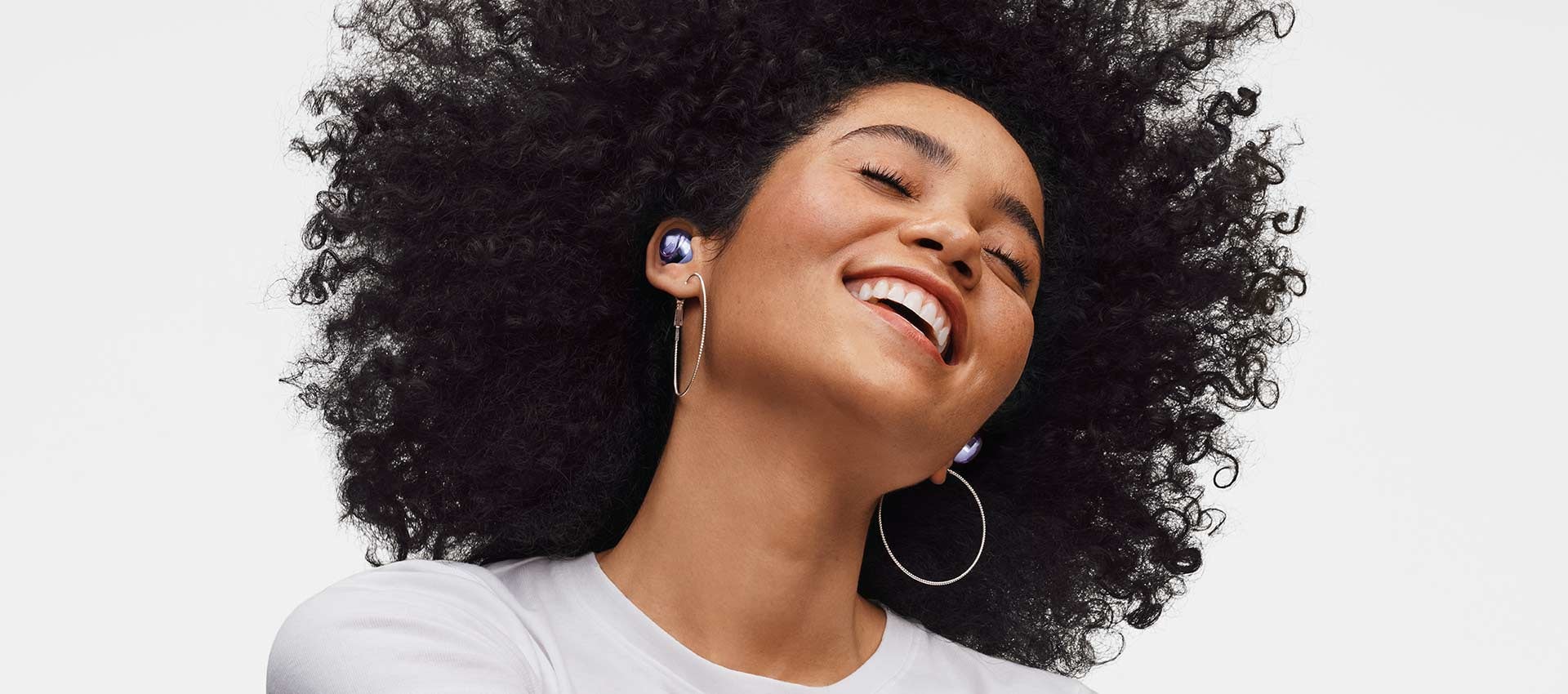 امرأة ترتدي سماعة Galaxy Buds Pro، وتدفع رأسها إلى الخلف وتبتسم.