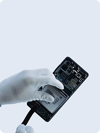 गैलेक्सी स्मार्टफोन के अंदर जाँच करते समय दस्ताने के साथ एक हाथ।