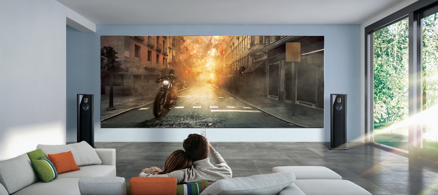 Una pareja mira una película de acción en la pared en una sala de estar