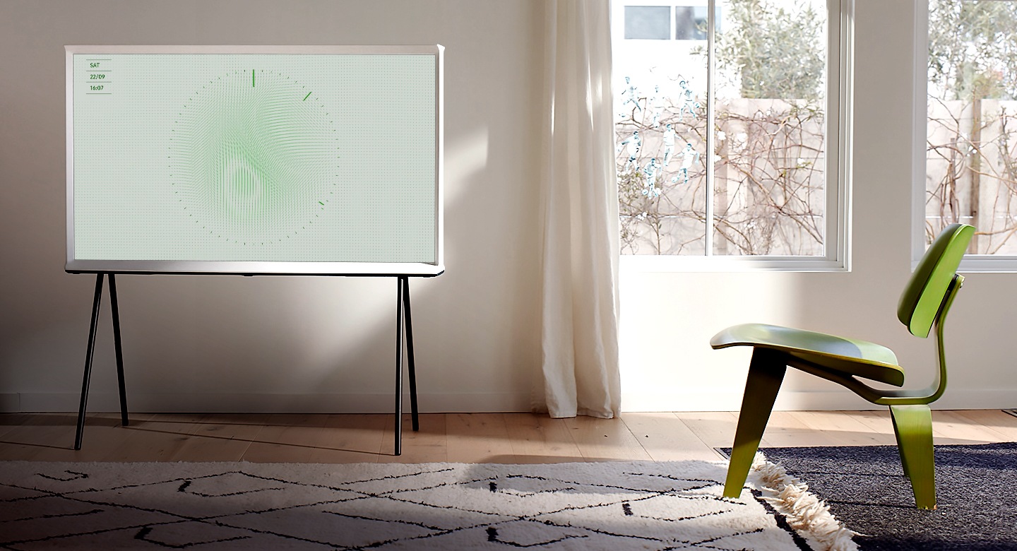 Eine weiße Modellwolke der Serife ruht auf einem schwarzen Fuß in einem hellen Wohnzimmer und einer eleganten Einfachheit mit einem dekorativen Teppich, einem schönen grünen Sessel mit drei Fuß und großen Fenstern. Das auf dem Bildschirm angezeigte Bild ist das Blatt 