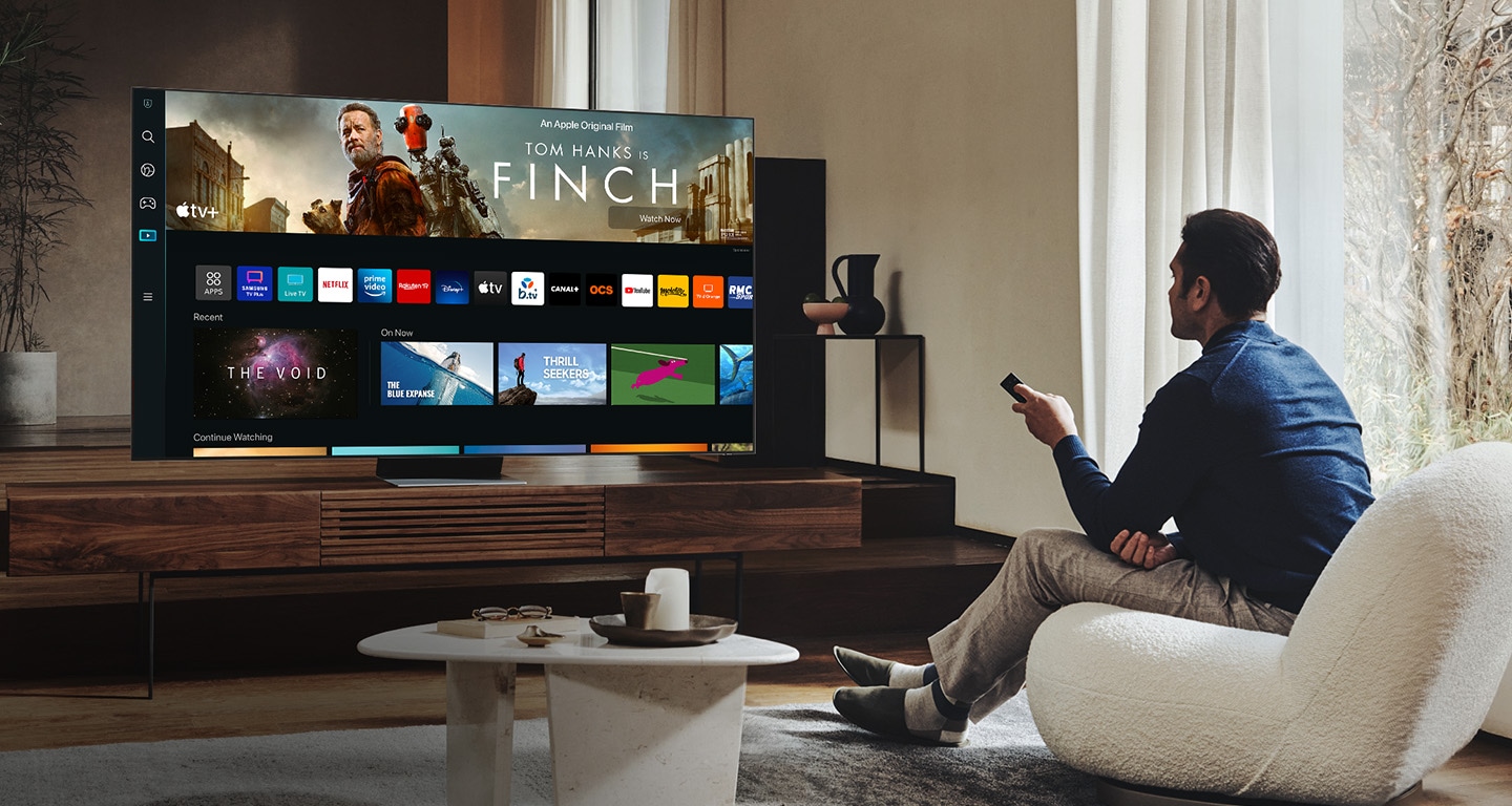 Un homme dans son salon regarde la nouvelle UI Smart TV sur son Neo QLED