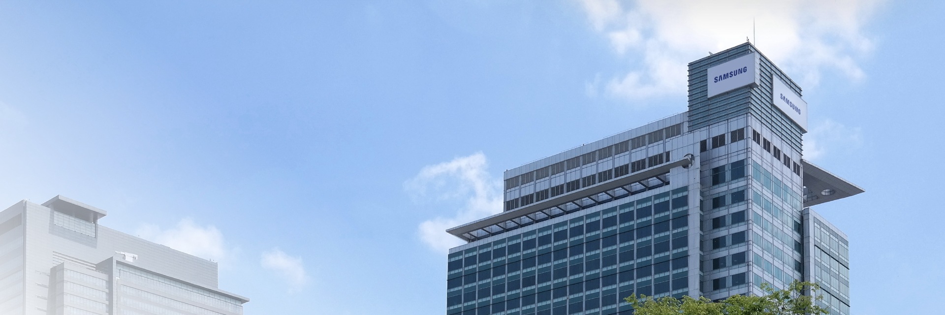 Velká, moderní kancelářská budova společnosti Samsung proti jasně modré obloze.