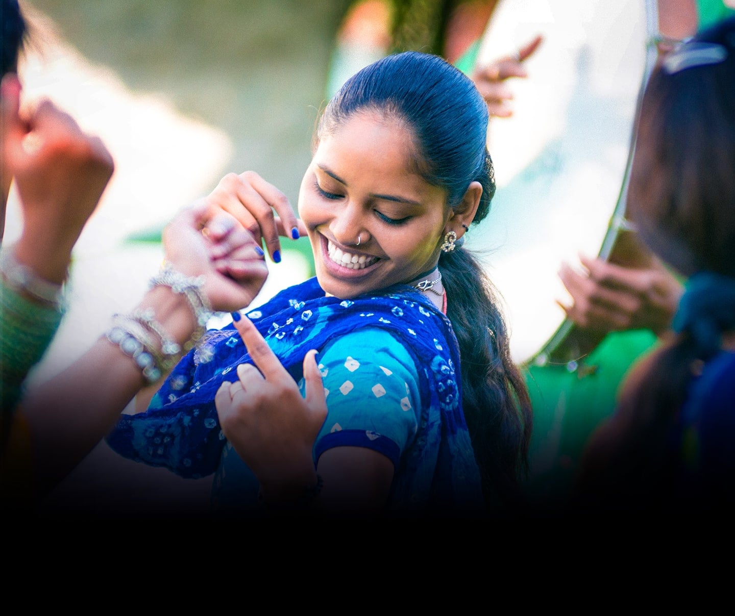 A photo image of a woman wearing a blue scarf smiling and dancing.