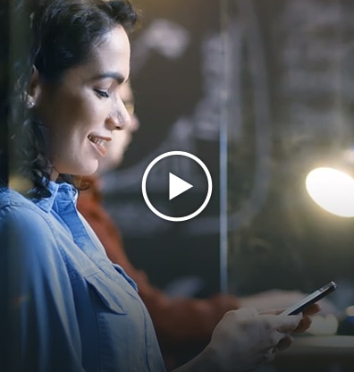 Video - A photo image of a woman smiling while looking at a cellphone