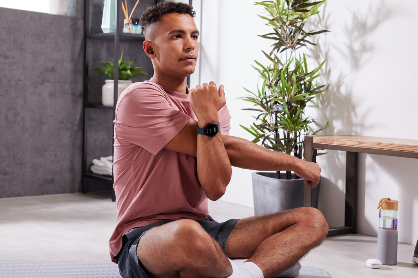 Mann in Sportkleidung mit Galaxy Buds2 beim Dehnen und Aufwärmen vor dem Training