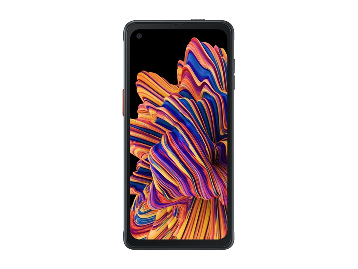 Смартфон Galaxy XCover Pro повышенной прочности стоит экраном, обращенным к камере, перед наполовину построенной бетонной комнатой.