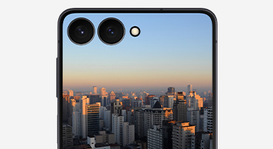 Η εξωτερική οθόνη ενός Galaxy Z Flip7 σε Jetblack δείχνει μια φωτεινή, ζωντανή εικόνα ενός αστικού τοπίου.