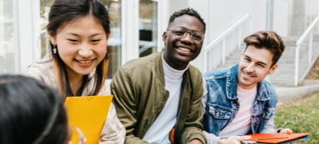 Four students stand together in a college environment, one of them holding a Samsung Galaxy Tab S7.