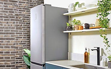  Samsung RB7300T hladnjak stoji pored kadetskih plavih umivaonika, a kuhinja izgleda minimalistički uređeno.
