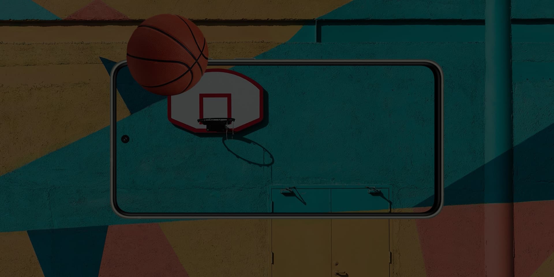 Scene of basketball next to a basketball hoop. The scene is seen on Galaxy S21 FE 5G’s screen and continues off-screen to demonstrate the realistic picture.