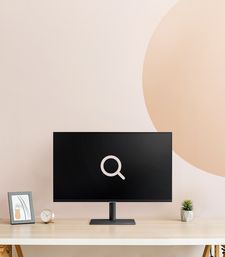 A beige-pink background. A monitor on top of the wooden table with a big search icon.