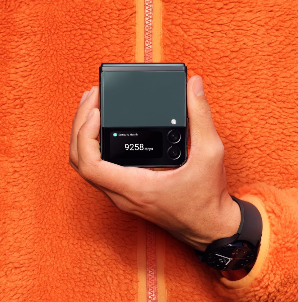 A hand holding Galaxy Z Flip3 5G folded with the step counter displayed on the Cover Screen.