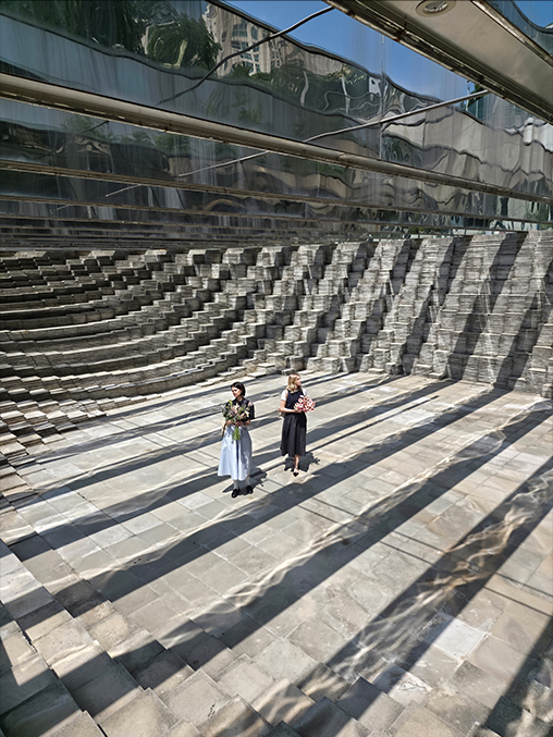 A portrait of two people has been shot using Galaxy Z Fold7's 200 megapixel rear camera against textured architecture. Vivid details and textures have been accurately captured.