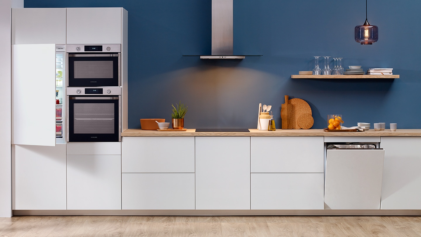 Un intero set di elettrodomestici da incasso Samsung come frigoriferi, forni, forni compatti, piani cottura, lavatrici e cappe installati in una cucina bianca premium.