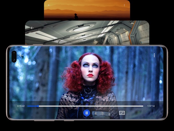 Front view of three Galaxy S10+ in landscape mode laid behind one another. On the front screen there is an video still of a red haired women in the middle of a jungle showing the experience of Infinity-O display.