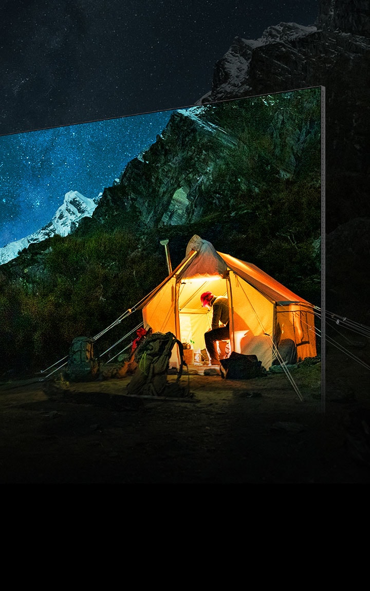 Un televisore mostra un’immagine nitida di un campeggiatore circondato da un grandioso scenario montuoso notturno. La vista mozzafiato sembra sconfinare oltre lo schermo.