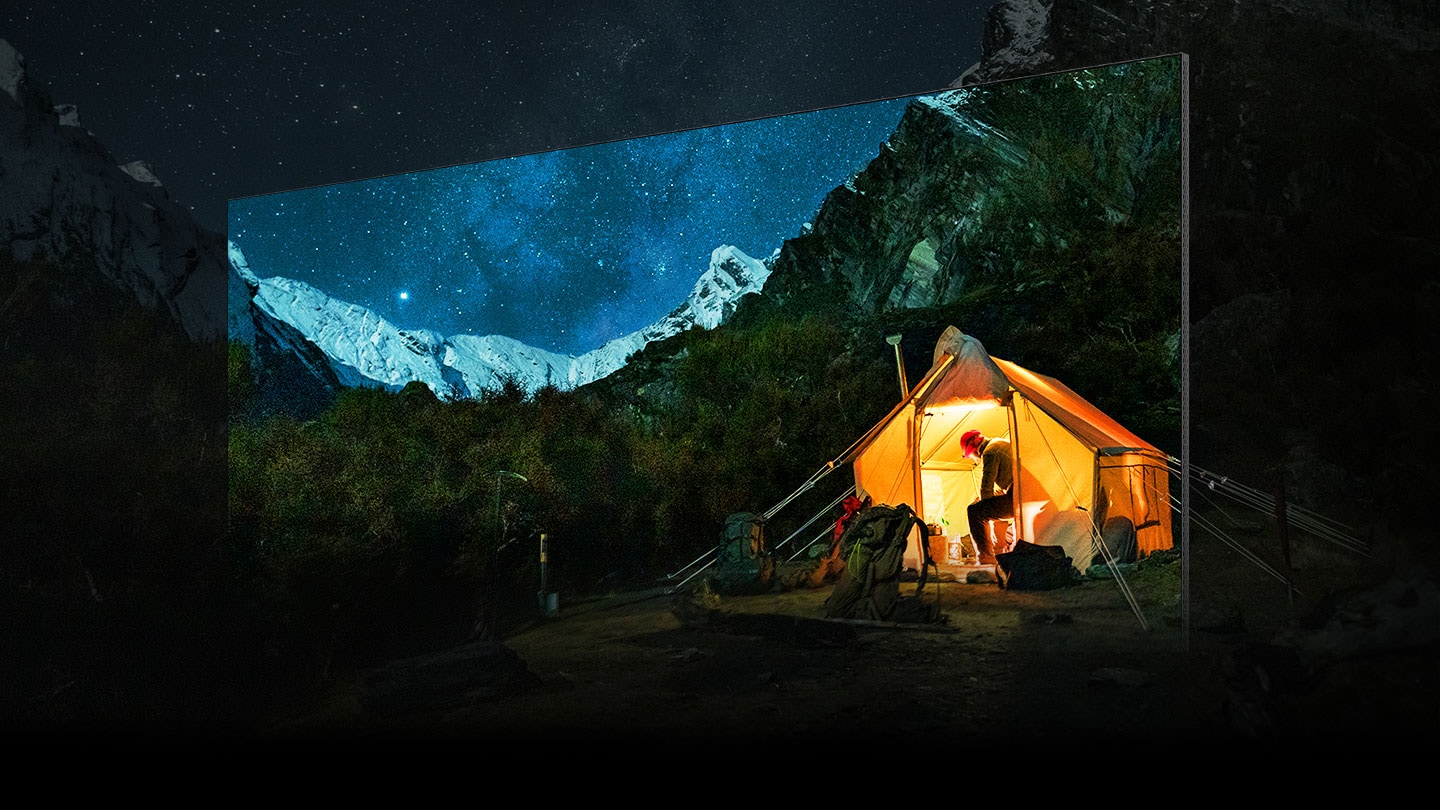 Un televisore mostra un’immagine nitida di un campeggiatore circondato da un grandioso scenario montuoso notturno. La vista mozzafiato sembra sconfinare oltre lo schermo.