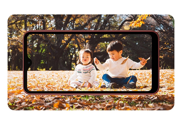 Galaxy A23 5G（ギャラクシーA23 5G）レッド製品ディスプレイの後ろから子供と二人が遊んでいる姿の写真が見えます。
