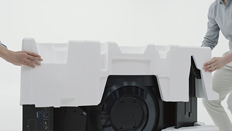 Два человека снимают пенопластовую крышку с монитора.