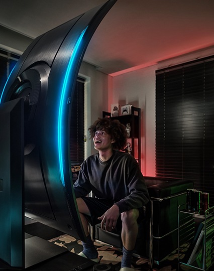 Мужчина стоит перед монитором и наслаждается им. Экран монитора вертикальный.