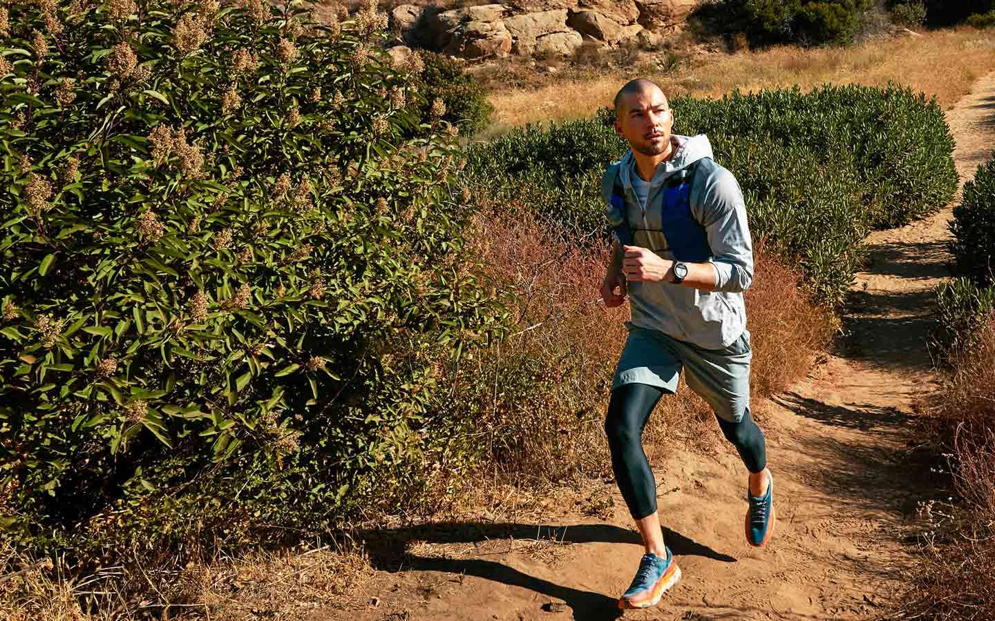 A man hiking downhill with a Galaxy Watch5 Pro on his wrist displaying the navigation feature.