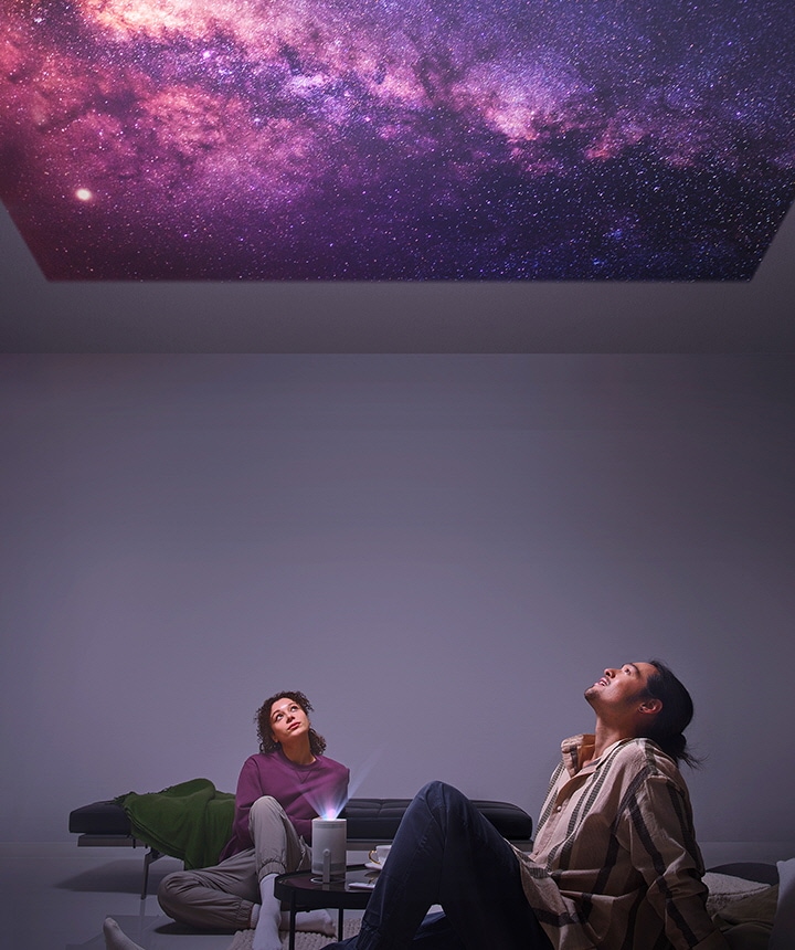 A man and woman stargaze at stars projected onto their ceiling from The Freestyle.