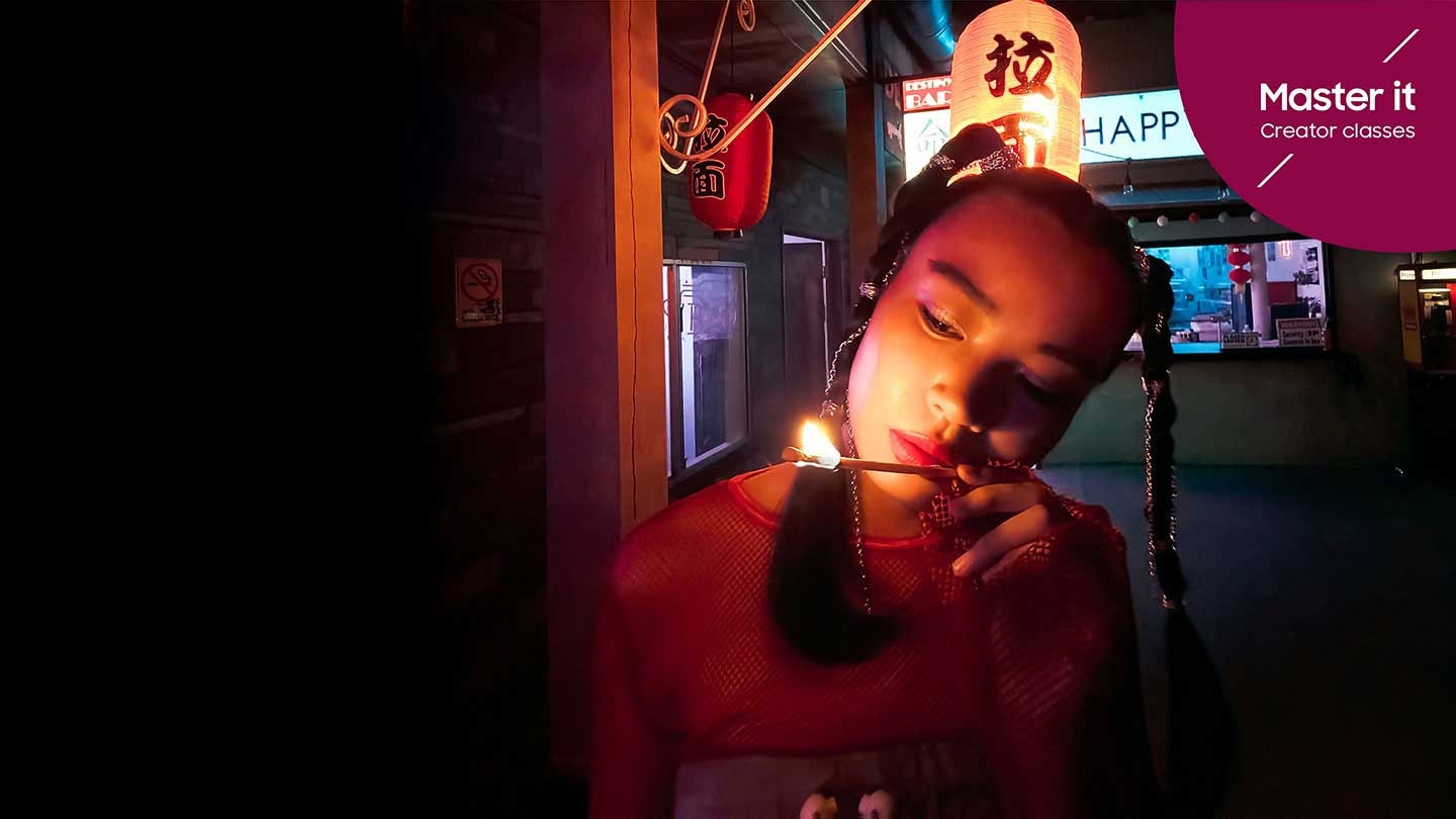 فتاة تحدّق في عود ثقاب طويل يشتعل في سوق مضاء بمصابيح نيون Master it. Creator classes.