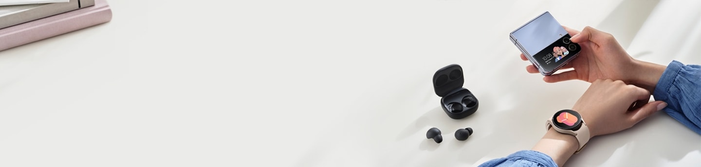 Vyras, laikantis „Galaxy Z Flip4“, segintis „Galaxy Watch“ ir naudojantis „Galaxy Buds“