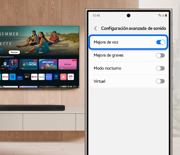 Phone screen displaying the Advanced Sound Settings in the SmartThings app, with the 'Voice enhancement' option toggled on, next to a Samsung Smart TV.