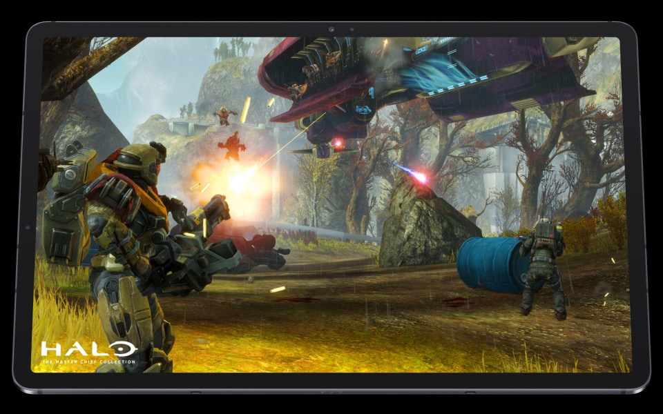 The tablet comes closer, giving you a front row seat to the action. Spaceships and robots appear on and off-screen to show how you become immersed in the game. The logo for Halo s is in the corner.
                            