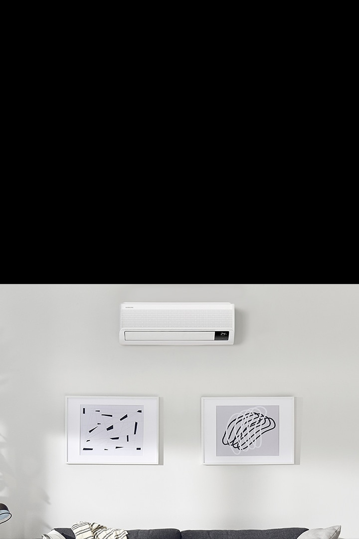wallmounted airconditioner is installed on the white wall and there is large sofa under the air conditioner.