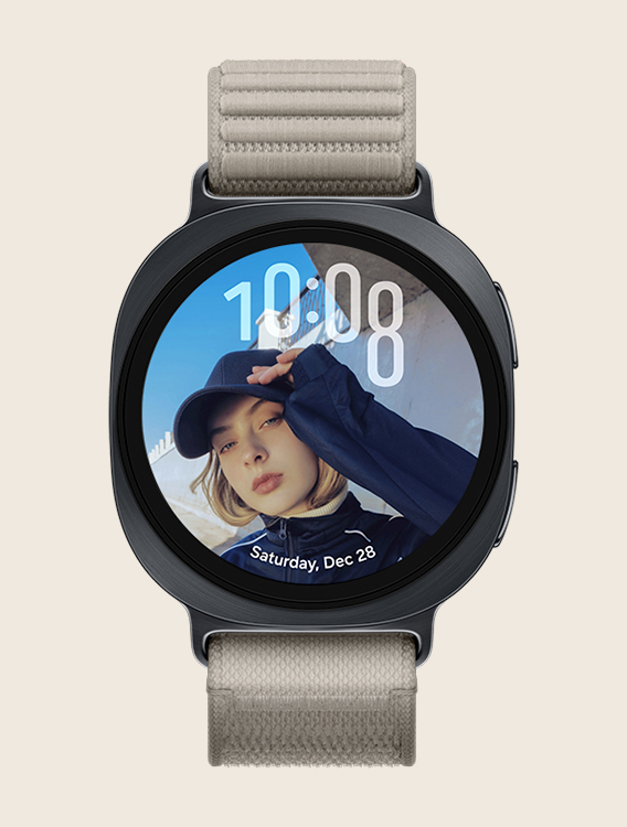 Front view and close-up angled view of Galaxy Watch9 with a Fabric Band in Mocha, displaying a custom Portrait Watch Face with the time at the top and date at the bottom, without overlapping with the person's face.
