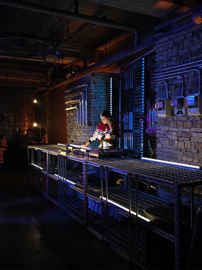 Une photo de nuit claire et colorée d’un DJ dans un lounge peu éclairé.