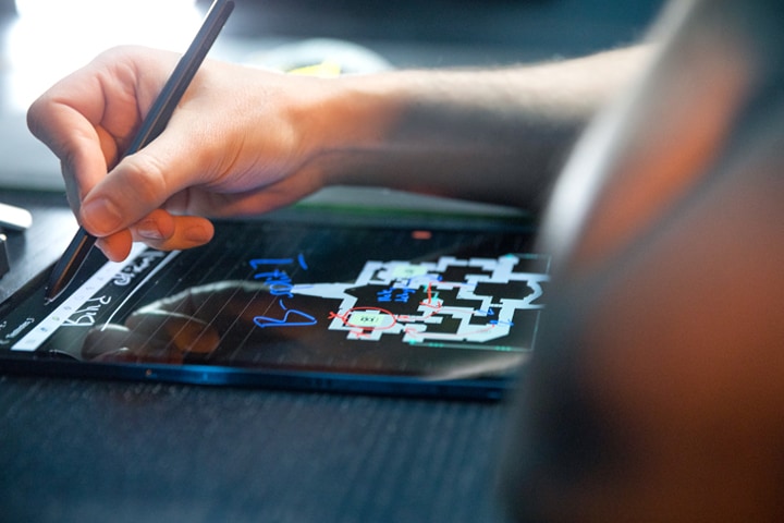 Et innzoomet bilde av en Tab S7 med en hånd over som holder i en S-pen for å notere en strategi.