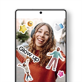 Centered is a Galaxy S25 Ultra displaying a gallery app screen with a selfie of a woman enjoying music and feeling free on the street. The photo is decorated with cute stickers including a stylish female character raises both arms, a male character spreads his arms, pink and yellow 3D star icons, a 3D white thumbs-up hand icon with a blue sleeve, a yellow face emoji with a satisfied expression, and a "Glow up" text sticker.