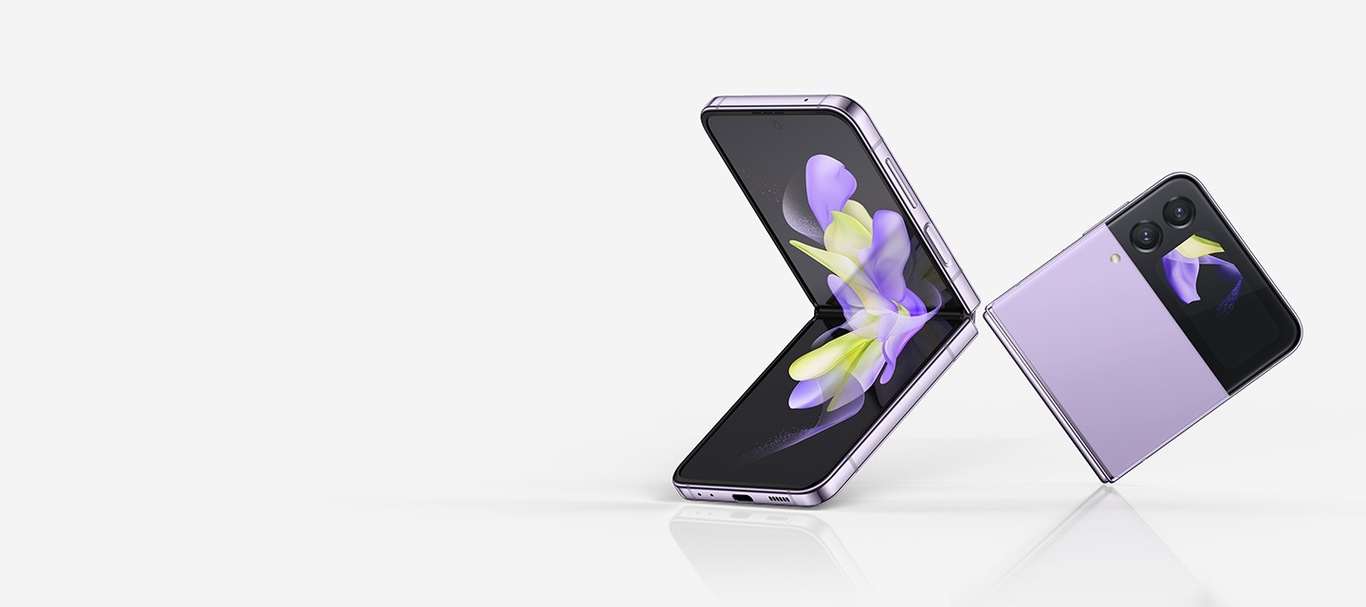 A Bora Purple Galaxy Z Flip4 opens to show a colorful, ribbon-like wallpaper on its Main Screen. It turns away, then folds closed. At the same time, a second Bora Purple Galaxy Z Flip4 emerges from behind it. They float near each other, one closed, and one open at a 90 degree angle. The folded device's cover screen and the Main Screen of the open device both display the same colorful, ribbon-like wallpaper.